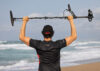 Nokta Legend 2 SMF metal detector held high by a man on a beach, featuring a carbon fiber shaft and search coil.
