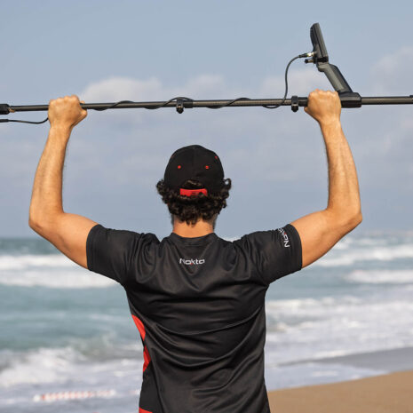 Nokta Legend 2 SMF Metal Detector Beach Performance Nokta Legend 2 SMF metal detector held high by a man on a beach, featuring a carbon fiber shaft and search coil.