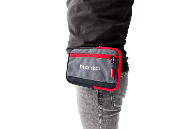 Nokta DetectoBag Hip Pouch Nokta DetectoBag hip pouch in grey and red with zippered pockets, worn on a belt for metal detecting accessories.