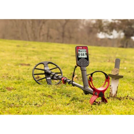 Nokta FINDX Pro Metal Detector for Land Detecting Nokta FINDX Pro metal detector on green grass with a digital screen showing target ID 68, a red armrest, and a digging tool nearby.